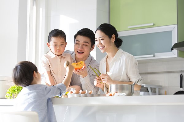 Family kitchen parentage. Young parents are playing with their son and daughter while cooking together. - stock photo